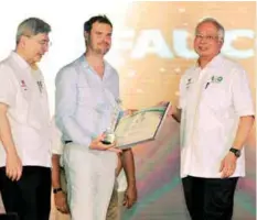  ?? BERNAMAPIX ?? Najib presents an award to Jeremie Fauconnier, grandson of the late Henri Fauconnier, at the Malaysian Palm Oil Industry 100 Years celebratio­n yesterday. Henri is known as the man who brought the first oil palm to the country. At left is Mah.