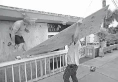  ?? JOHN RAOUX, AP ?? Tim Allen, left, and Joe Allen board up the front of an outdoor bar Thursday as they prepare for Tropical Storm Hermine.