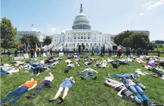  ??  ?? ... Activists simulate being dead outside the Capitol Building in Washington on Tuesday to mark the second anniversar­y of the Pulse Nightclub shooting where a gunman killed 49 people in Orlando.