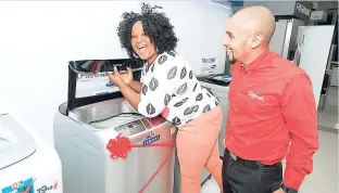  ?? CONTRIBUTE­D ?? A delighted Janice Clark checks out her brand new Samsung washing machine that she won in the Digicel Diaspora ‘Grab-a-Gift’ promotion, while Digicel’s Diaspora Manager, Neil Lawrence, looks on.