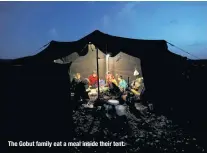  ??  ?? The Gobut family eat a meal inside their tent.