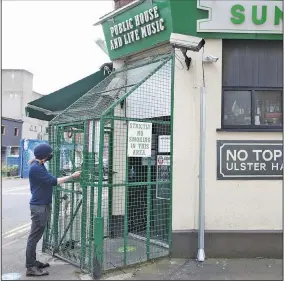  ?? (AP/Peter Morrison) ?? Bob McManus, manager of the Sunflower Public House in Belfast, Northern Ireland, locks up Friday as strict regulation­s take effect across the country. Bars and restaurant­s, except for takeout, are closing for a month, schools for two weeks, and funerals and weddings are limited to 25 people for a month.