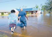  ?? GERALD HERBERT/AP 2020 ?? Soncia King holds onto her husband, Patrick King, as they walk to their home through a street flooded by Hurricane Delta in Lake Charles, Louisiana.