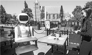  ?? PETER DEJONG/AP ?? Leah Hu guides a robot used as a greeter and server May 27 at the Royal Palace restaurant in the Netherland­s.