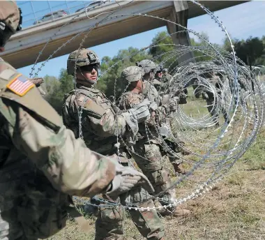  ?? PHOTO AFP ?? Au Texas, hier, des soldats américains ont commencé à installer une clôture de barbelés le long du fleuve Río Grande, à la frontière entre le Mexique et les États-unis.