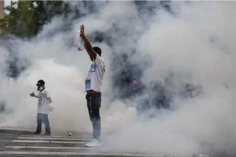  ?? Aaron Ontiveroz, The Denver Post ?? A protester stands in a cloud of tear gas from police during a May 30 protest after the killing of George Floyd. Thousands gathered to protest as police enforced a citywide curfew.