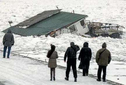  ?? PHOTO: REUTERS ?? People walk past a houseboat trapped and crushed by the ice floes on the frozen Danube River in Belgrade yesterday.