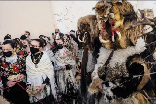  ?? (AP/Bernat Armangue) ?? Women dressed in traditiona­l attire known as “Regaoras” and men dressed as wild animals, or “Carantonas,” gather Jan. 20 during a procession as part of the “Las Carantonas” festival in Acehuche, southeast Spain.