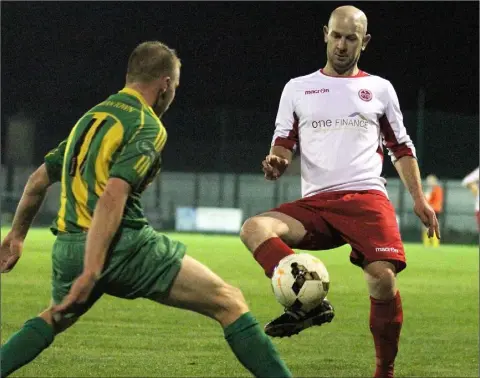  ??  ?? David Ward of Rock Celtic lays the ball off as Navan Town’s Jamie Power closes in.