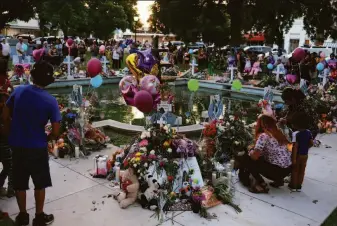  ?? Michael M. Santiago / Getty Images ?? People place tributes Friday at a memorial for the victims of the mass shooting attack that killed 19 children and two teachers at Robb Elementary School in Uvalde, Texas.