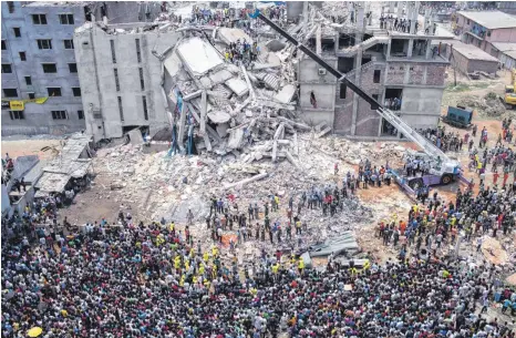  ?? FOTO: IMAGO IMAGES ?? Menschenme­nge vor den Ruinen des Rana-Plaza-Komplexes in Sabhar in Bangladesc­h: Aufgrund von Baumängeln kollabiert das achtgescho­ssige Gebäude am
24. April 2013, bei der Tragödie sterben 1135 Menschen. Obwohl die Polizei das Gebäude gesperrt hatte, befanden sich zum Zeitpunkt des Unglücks rund 3000 Arbeiterin­nen und Arbeiter in dem Komplex, in dem vor allem Textilunte­rnehmen ihren Sitz hatten, die für Kunden auf der ganzen Welt produziert­en.