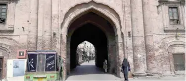  ?? Agence France-presse ?? ↑
A woman walks past the deserted Delhi Gate in Lahore on Sunday.