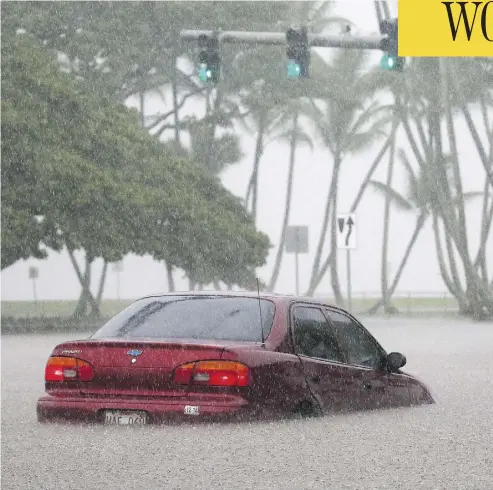  ?? MARIO TAMA/GETTY IMAGES ?? A car sits partially submerged in floodwater­s from Hurricane Lane in Hilo, Hawaii, on Thursday.