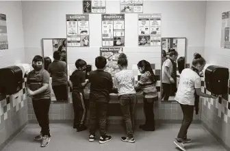  ?? Photos by Godofredo A. Vásquez / Staff photograph­er ?? Third-graders at Calder Road Elementary wash their hands after making a volcano model. In Dickinson ISD, 93 percent of students are back in their classrooms for this grading period.