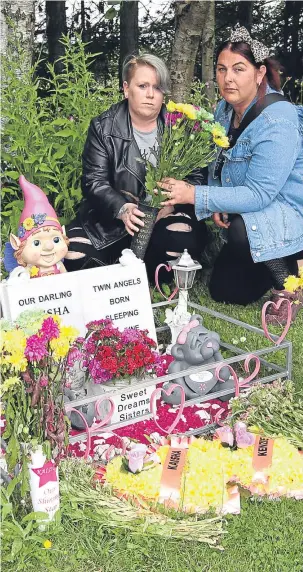  ??  ?? Lisa and Katie place flowers where Lisa’s twins are buried at the cemetery.