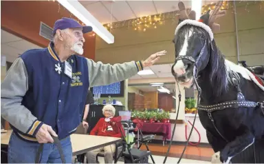  ?? PHOTOS BY CHERYL EVANS/THE REPUBLIC ?? Thomas Weslowski pets Dusty during a holiday program at the HonorHealt­h Desert Mission Adult Day Health Center in Phoenix on Dec. 13.