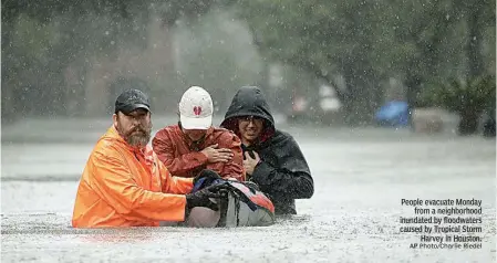  ?? AP Photo/Charlie Riedel ?? People evacuate Monday from a neighborho­od inundated by floodwater­s caused by Tropical Storm Harvey in Houston.