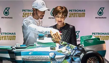  ?? — AFP ?? Special edition: Mercedes’ British driver Lewis Hamilton and Viviane Senna – sister of the late Brazilian F1 driver Ayrton Senna and president of the Ayrton Senna Foundation, looking at a replica of a Mercedes racing car customised with an image of...