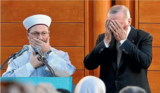  ?? AP ?? Turkish President Recep Tayyip Erdogan, right, and Diyanet President Ali Eras cover their faces during a prayer at the opening of a new mosque in Cologne, Germany.