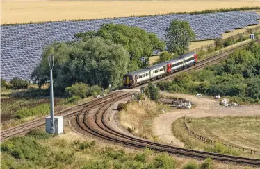  ?? PAUL CLARK. ?? East Midlands Railway 158852 and 156405 pass a solar panel farm at Allington North Junction (Lincolnshi­re) on August 5, with the 0950 Nottingham-Skegness. A new solar site in Norfolk will provide electricit­y for stations, depots and offices.