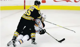  ??  ?? Edmonton Oilers centre Leon Draisaitl tries to control the puck as he is knocked to the ice by Boston Bruins centre Noel Acciari during the third period of Sunday’s game in Boston.