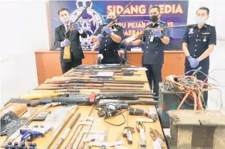  ??  ?? Simiun Lomudin (second from le ) showing the 20 homemade shotguns, air rifles and marble rifles which were seized in the raids.