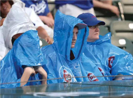  ?? CHARLES REXARBOGAS­T/ AP ?? Fans sit through a lengthy delay before the Cubs’ series opener Monday against the Dodgers atWrigley Field was postponed by rain.