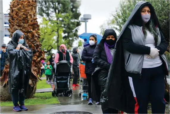  ?? AFP ?? Juana Gomez, left, 50, wears a face mask and gloves as she waits to receive food at a food bank distributi­on for those in need as the coronaviru­s pandemic continues in Van Nuys, California.