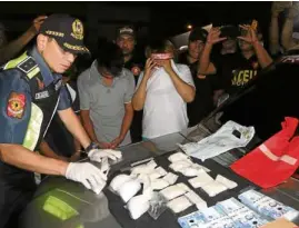  ?? —PHOTOCOURT­ESY OFNCRPO ?? BUY-BUST HAUL Police Maj. Gen. Guillermo Eleazar, Metro Manila police chief, inspects the drugs and cash seized from three suspects in Mandaluyon­g City.