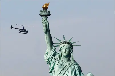  ?? AP PHOTO ?? A tourist helicopter circles the Statue of Liberty in New York. The statue is closed due to the government shutdown.