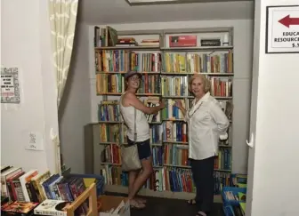  ?? (Submitted photo) ?? Starkville Friends of the Library board member and July sales chair, Betty Lynn Hunt, shows library patron Tammi Looney some of the selections available in the new Education Resource Center. The center will be featured in the monthly book sale Monday,...