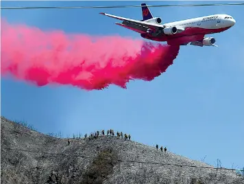  ?? The Associated Press ?? A DC-10 Air Tanker swoops in to make a retardant drop as it passes above firefighti­ng ground crews on a ridge fighting the South Fire on Thursday near Lytle Creek, Calif.