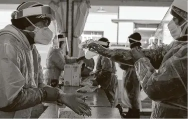  ?? Calla Kessler / New York Times ?? Medical workers sanitize themselves before testing for the coronaviru­s at a mall in Omaha, Neb. More than 1,000 Americans are dying of the coronaviru­s every day on average, a 50 percent increase in the last month.