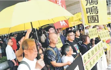  ??  ?? Pro-democracy supporters hold yellow umbrella to support leaders of Occupy Central activists, outside the court, in Hong Kong, China.