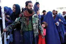  ?? AP FILE PHOTO ?? HELP AMID HARDSHIP
A Taliban fighter stands guard as people receive food rations distribute­d by a Saudi humanitari­an aid group in Afghanista­n’s capital Kabul on April 25, 2022.