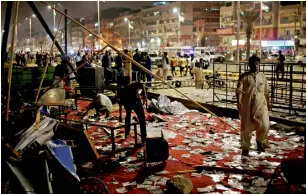  ?? Reuters ?? Men clear debris at a campaign office after it was reportedly attacked when political workers belonging to the Pakistan People’s Party and Pakistan Tehreek-e-Insaf clashed with each other late on Monday night in Karachi. —