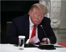  ?? AP FILE ?? DIRECT MESSAGING: President Trump looks at his phone during a roundtable with governors at the White House in Washington, D.C., on June 18. Though stripped of his Twitter account for inciting rebellion, Trump does have alternativ­e options of much smaller reach.