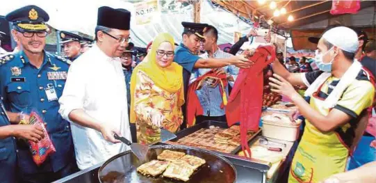  ?? [FOTO ZULKEPLI OSMAN/BH] ?? Abdul Rahman diiringi Ketua Pengarah Jabatan Bomba dan Penyelamat Malaysia, Datuk Wan Mohd Nor Ibrahim (kiri) menyampaik­an peralatan keselamata­n kepada peniaga bazar Ramadan di Padang MPK1, Kuantan, kelmarin.