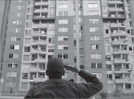  ?? Photo: AFP ?? A police officer salutes as he dances encouragin­g people to follow him from their balconies and windows as the force visits the neighborho­od to cheer people up during the lockdown imposed as a preventive measure to curb the spread of COVID-19 in Bogota, Colombia on Wednesday.