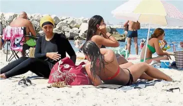  ??  ?? No big deal: A woman dressed in a burkini (left) lounging on a beach in Marseille, France. — AP