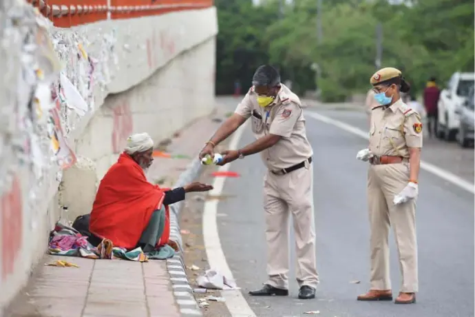 ?? © belga/Hindustran Times ?? De politie in Delhi deelt handontsme­ttingsgel uit aan een dakloze.