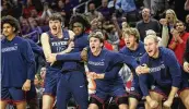  ?? DAVID JABLONSKI / STAFF ?? Dayton players on the bench react to a dunk by DaRon Holmes II against Northweste­rn on Friday at Welsh-Ryan Arena in Evanston, Illinois.