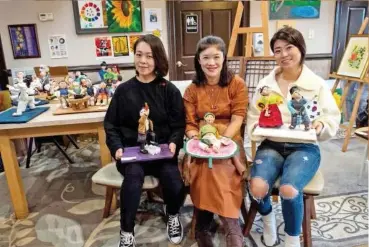  ?? Tribune News Service Tribune News Service ?? ↑
Artists Hyekyong ‘Heather’ Yun (left), Sujoung ‘Christine’ Paek and Enjung ‘Jenny’ Lee pose with their artwork.