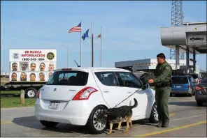  ?? AP/NOMAAN MERCHANT ?? A Border Patrol agent inspects a car waiting to pass through the Laredo North vehicle checkpoint earlier this month in Laredo, Texas.