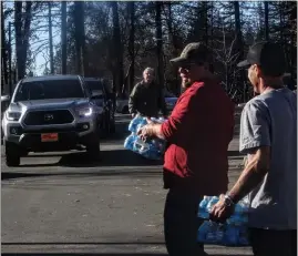  ?? FILE/PARADISE POST ?? Tom McIntyre and Joel Burkett load bottled water for PID customers in 2019in Paradise, California. The Paradise Irrigation District had been providing drinking water to its customers since the Camp Fire. On Friday, PID said it will now more closely monitor its free water fill station due to the drought.