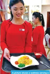  ??  ?? A picture shows a waitress serving a dish to patrons.