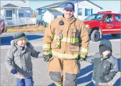  ??  ?? Rod McNeil with the Reserve Mines Volunteer Fire Department, escorts Jace Fortune, left, and Tyler Boutilier back to Tompkins school following Christmas dinner at the Reserve Mines Seniors and Pensioners Club. The firefighte­rs escorted all 230 students to and from the meal.