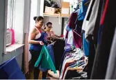  ??  ?? Volunteers put away clothes at the God’s Closet thrift store operated by the Bridgeport church.