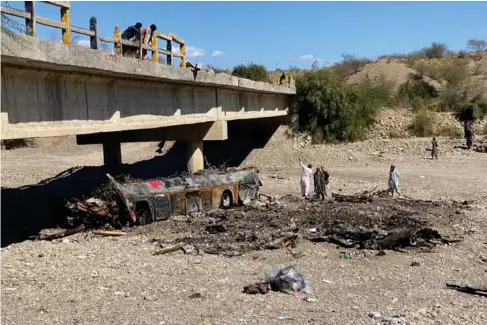  ?? AFP via Getty) ?? Residents look at the wreckage of a burnt passenger bus i nB aloc hist an(