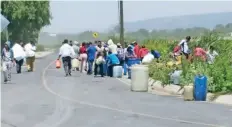  ??  ?? En camionetas y a pie, los saqueadore­s llegaron con botes, cubetas, garrafones y bidones para recolectar la gasolina frente a los agentes.